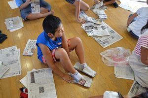 手づくりした新聞紙スリッパを試し履き